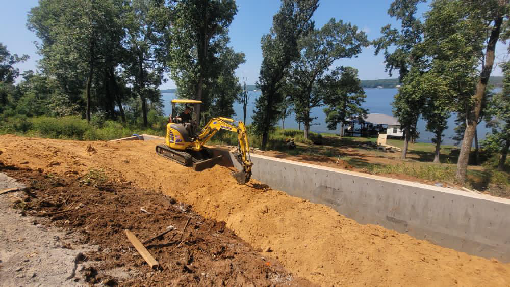 A member of the Landworks Landscapes team digs out soil next to a newly built retaining wall.